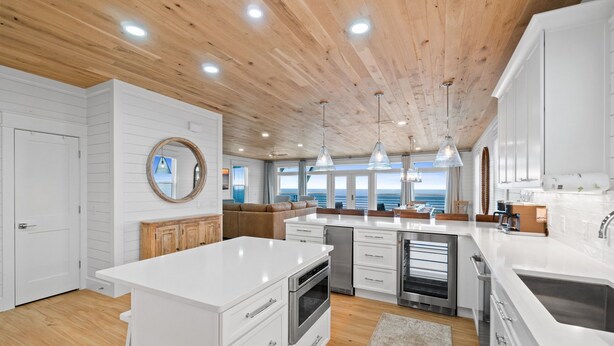 Een moderne keuken met witte kasten, een houten plafond en hanglampen.