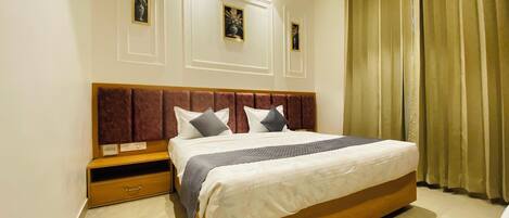 A modern bedroom with a large bed, wooden headboard, and a nightstand.