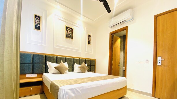 A neatly arranged bedroom with a large bed, a wooden headboard, and a bedside table. - Hotel MJ MARRIOTS (Amritsar)