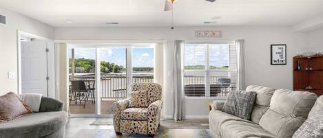 A spacious living room with a ceiling fan, a sofa, a chair, and a view through large windows.