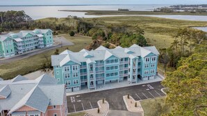 A multi-story hotel with a parking lot and a view of a body of water. - Hamilton Cay Reserve at Bermuda Bay (Kill Devil Hills)
