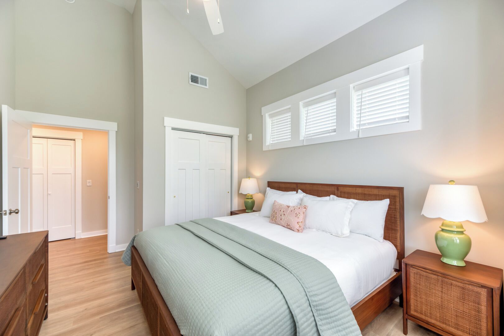 A bedroom with a bed, two bedside tables with lamps, a wardrobe, and a door.