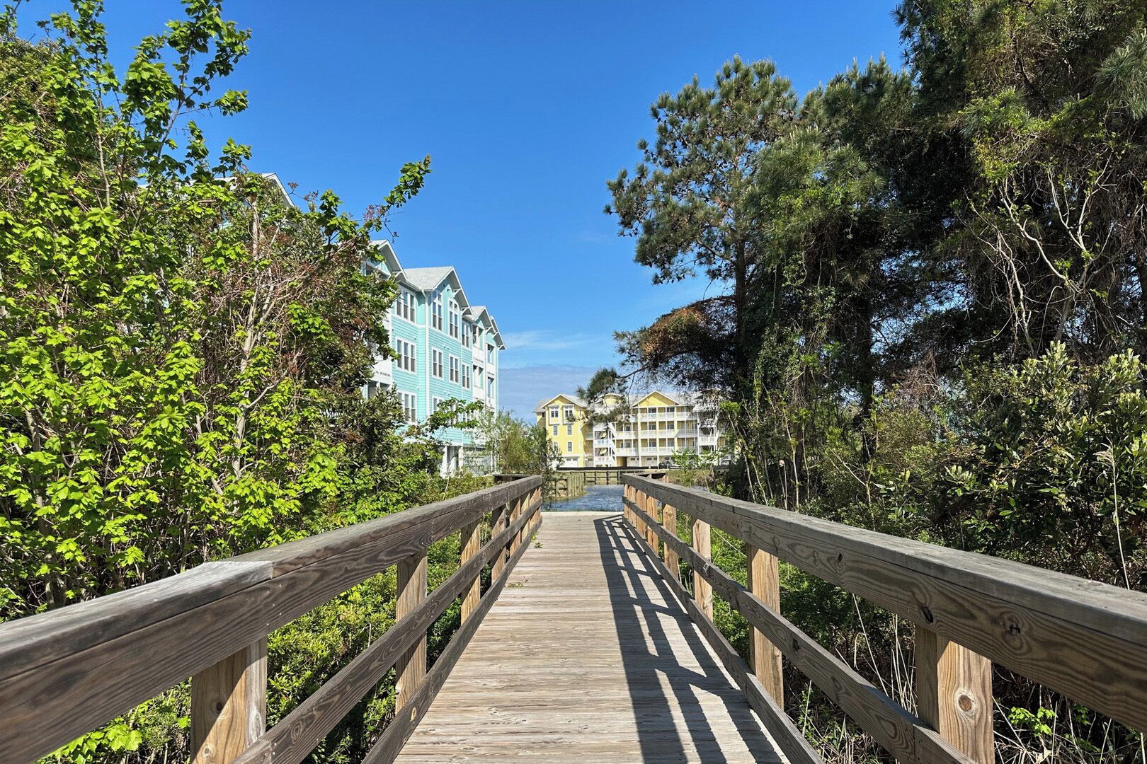 A wooden boardwalk leading to a row of buildings with multiple stories and balconies.