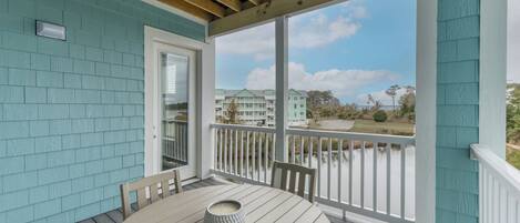 A covered outdoor area with a table and chairs, a door, and a view of a lake and buildings in the background.