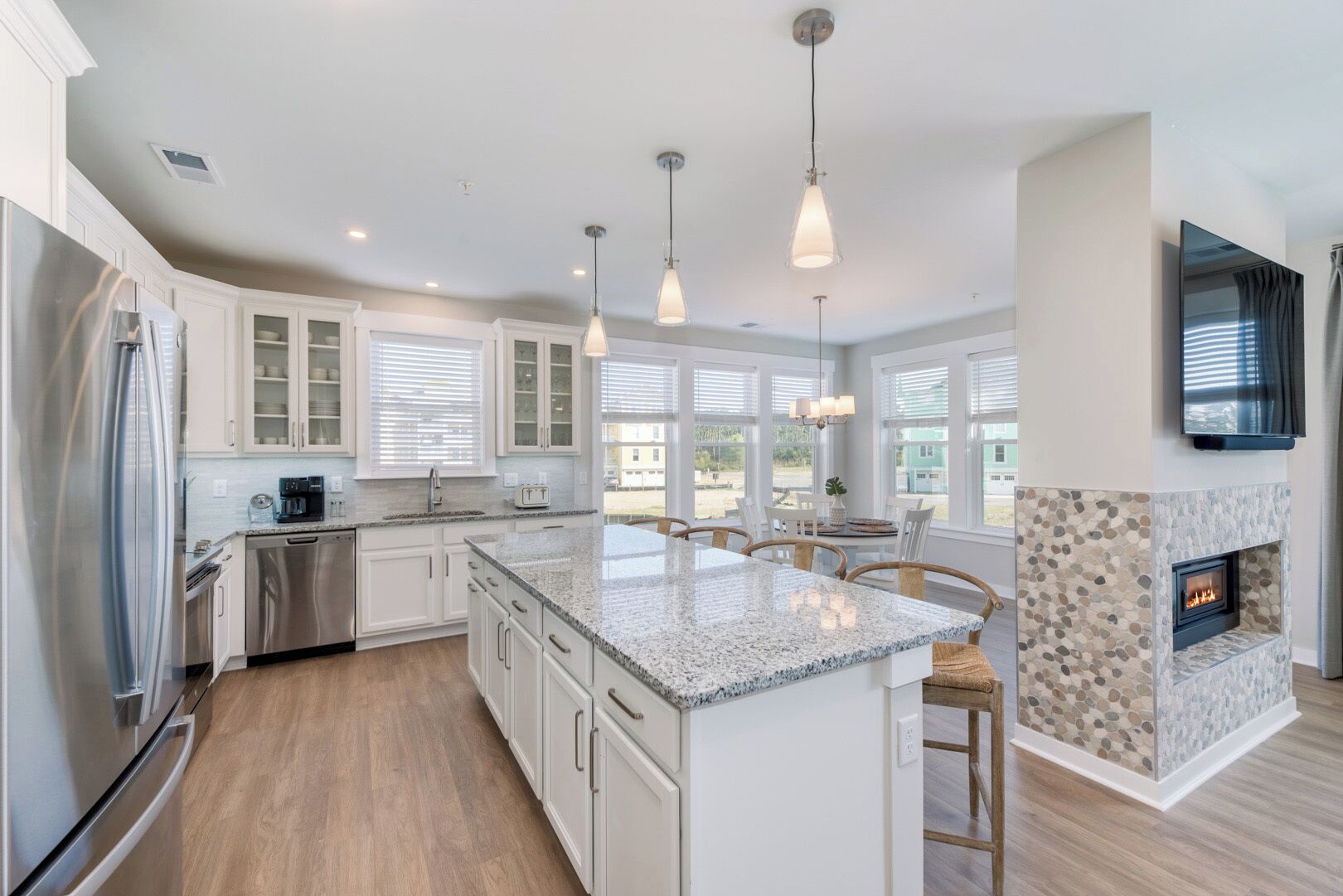 A modern kitchen with granite countertops, stainless steel appliances, and a stone fireplace.