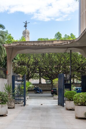 An entrance with a covered walkway, a statue, and potted plants. - Vittorio Veneto Apartment by Wonderful Italy (Palermo)
