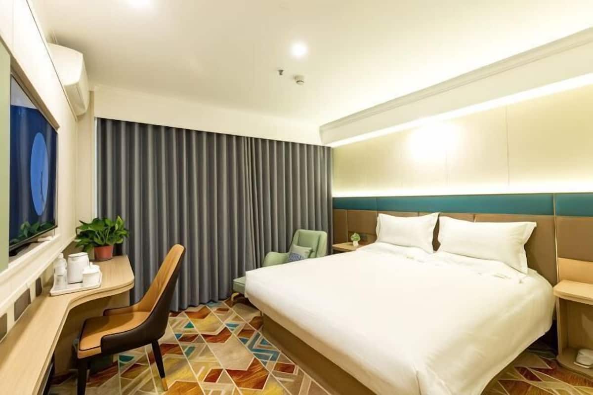 A hotel room with a bed, desk, chair, and a television.