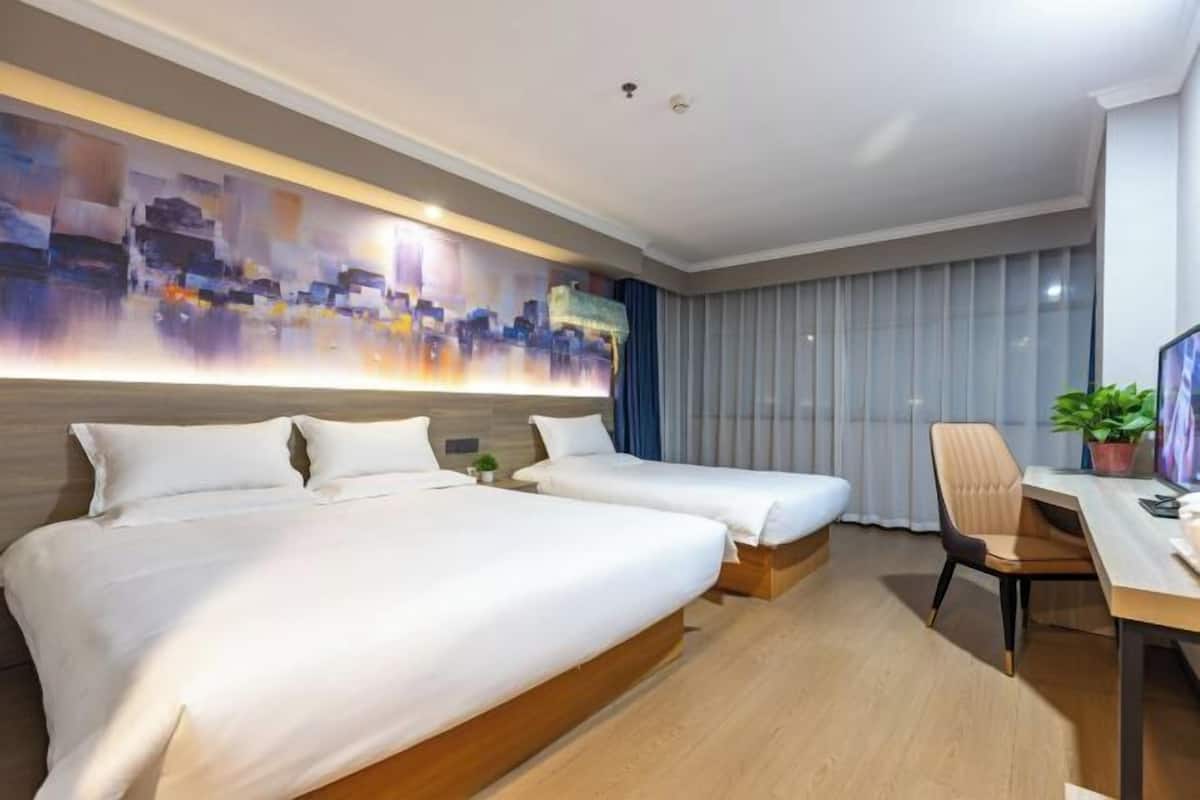 A hotel room with two beds, a desk, a chair, and a large abstract painting on the wall.