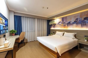 A modern hotel room with a large bed, a desk with a computer, and a cityscape artwork on the wall. - ning zhao Hotel (Shijiazhuang Railway University Subway Station) (Shijiazhuang)