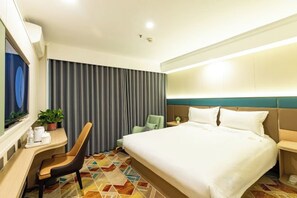 A hotel room with a bed, a desk, a chair, a TV, and a curtain.