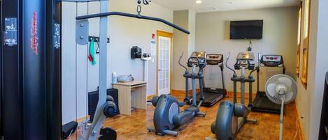A gym with exercise equipment, treadmills, and a fan.