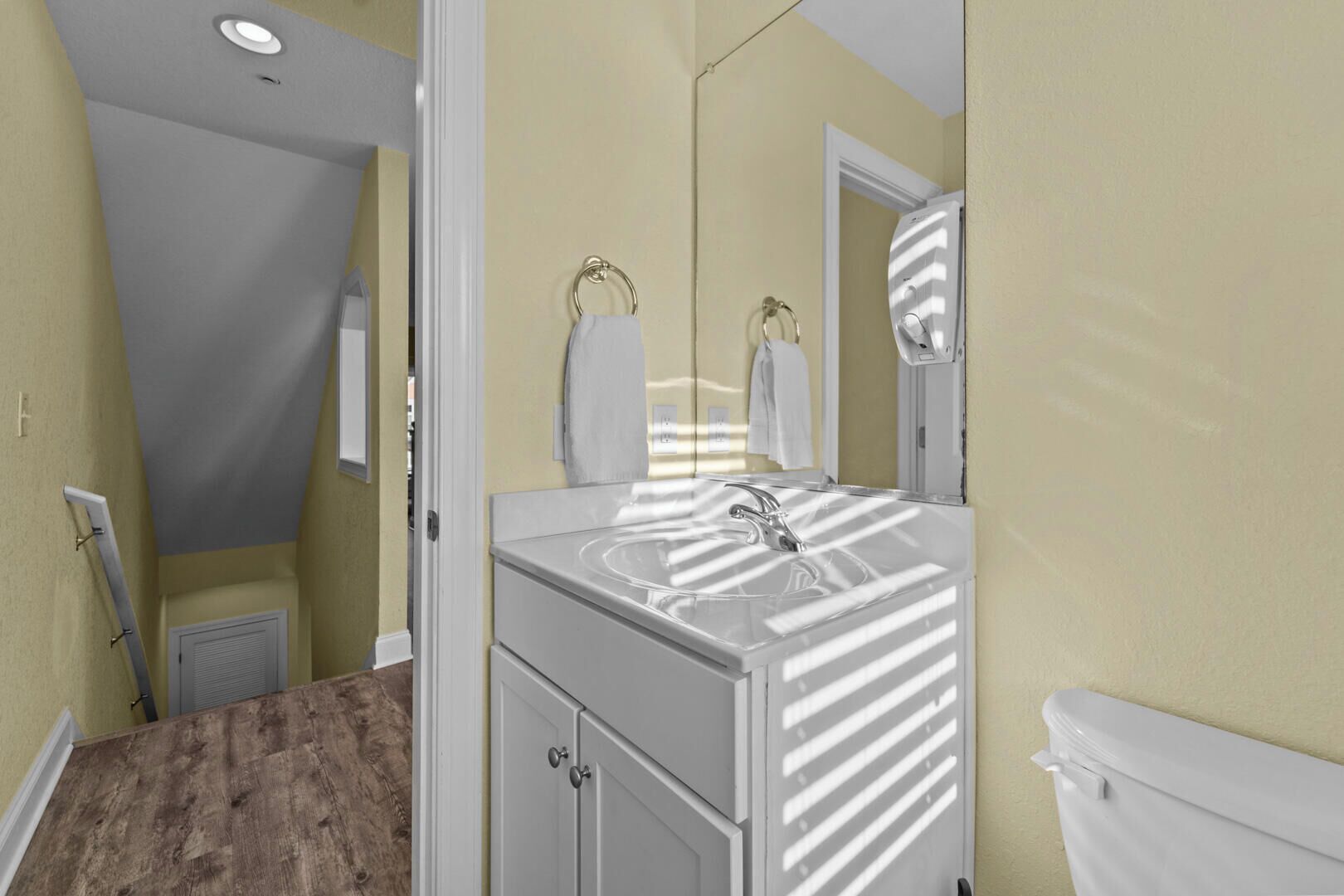 A bathroom with a white vanity, a sink, a mirror, and a toilet.