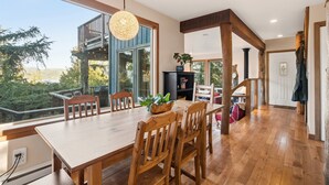 Un comedor amplio con una gran mesa de madera y sillas, una lámpara colgante y vistas al exterior.