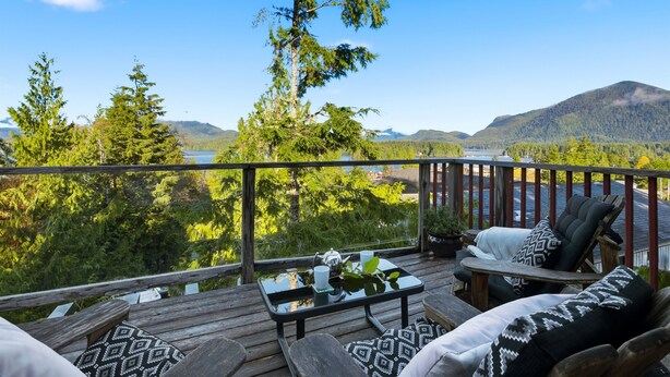 Una terraza con mobiliario exterior, una mesa con tetera y taza, y vistas a un lago y montañas.