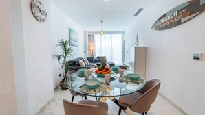 Un espace repas moderne avec une table en verre, des chaises marron et un saladier rempli de fruits.