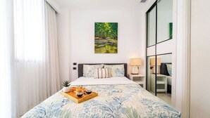 Une chambre d’hôtel avec un lit, un tableau, un plateau avec des en-cas et une vue sur l’extérieur.