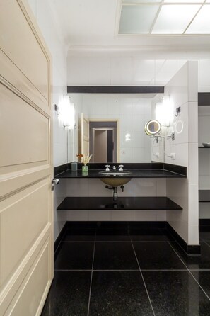 A modern bathroom with a black countertop, a sink, and a mirror with lights.