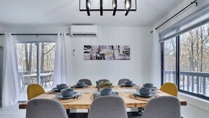 A dining area with a wooden table set for six, grey chairs, and a modern chandelier. - Starlight Chalet | Game Room | Pool Access | AC (Tobyhanna)