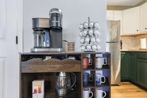 A kitchenette with a coffee maker, a mug rack, and a coffee card box.