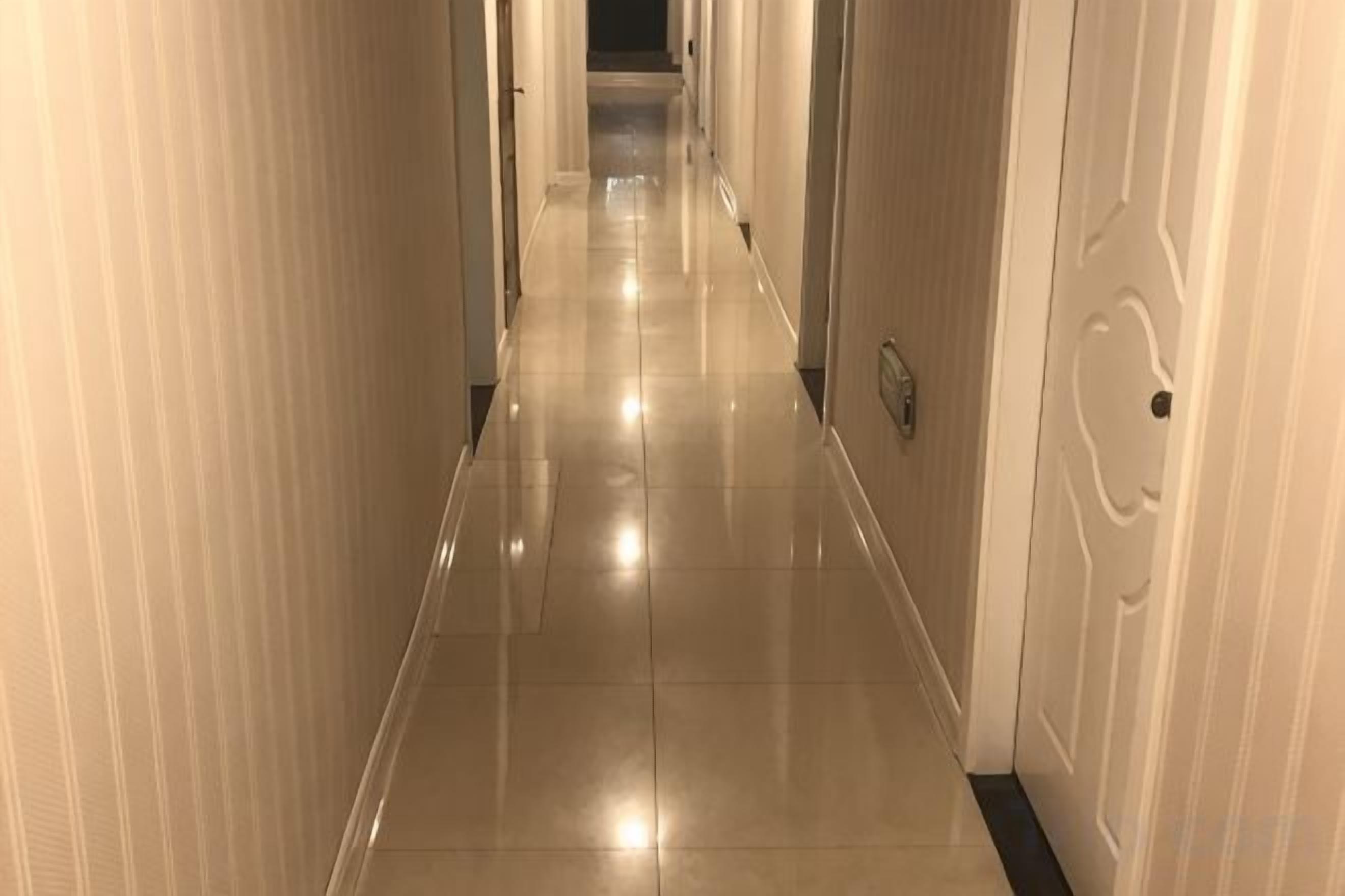 Un pasillo largo y estrecho con piso brillante y puertas a ambos lados.