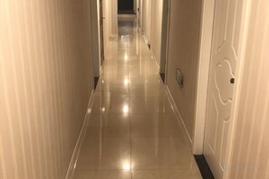 Un long couloir étroit, doté d’un sol brillant et de portes de part et d’autre.