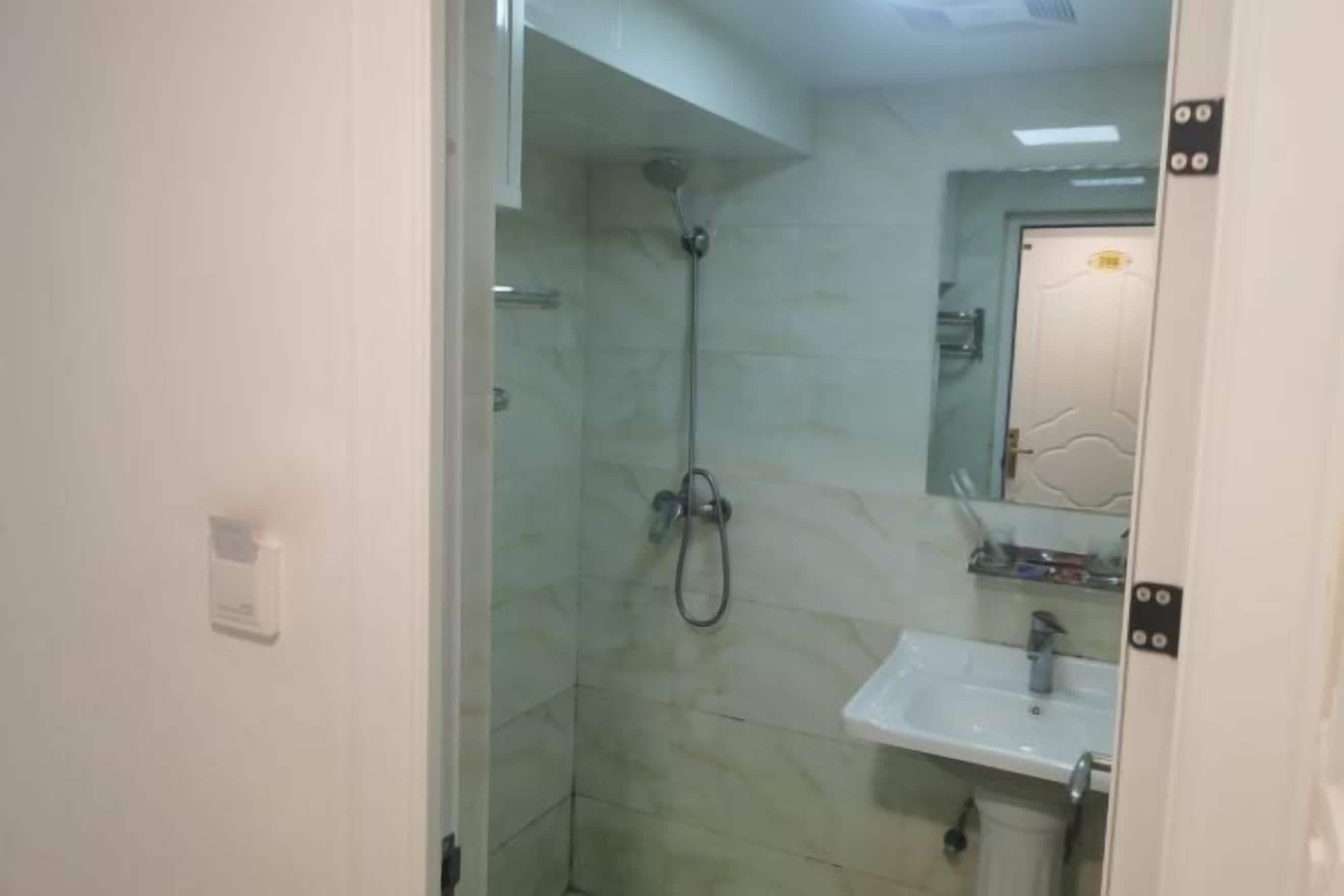 A bathroom with a glass shower enclosure, a white sink, and a mirror above it.