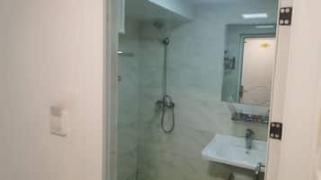 A bathroom with a glass shower enclosure, a white sink, and a mirror above it.