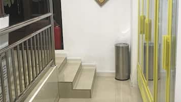 A staircase with a metal railing, a trash bin, and a yellow-framed window.