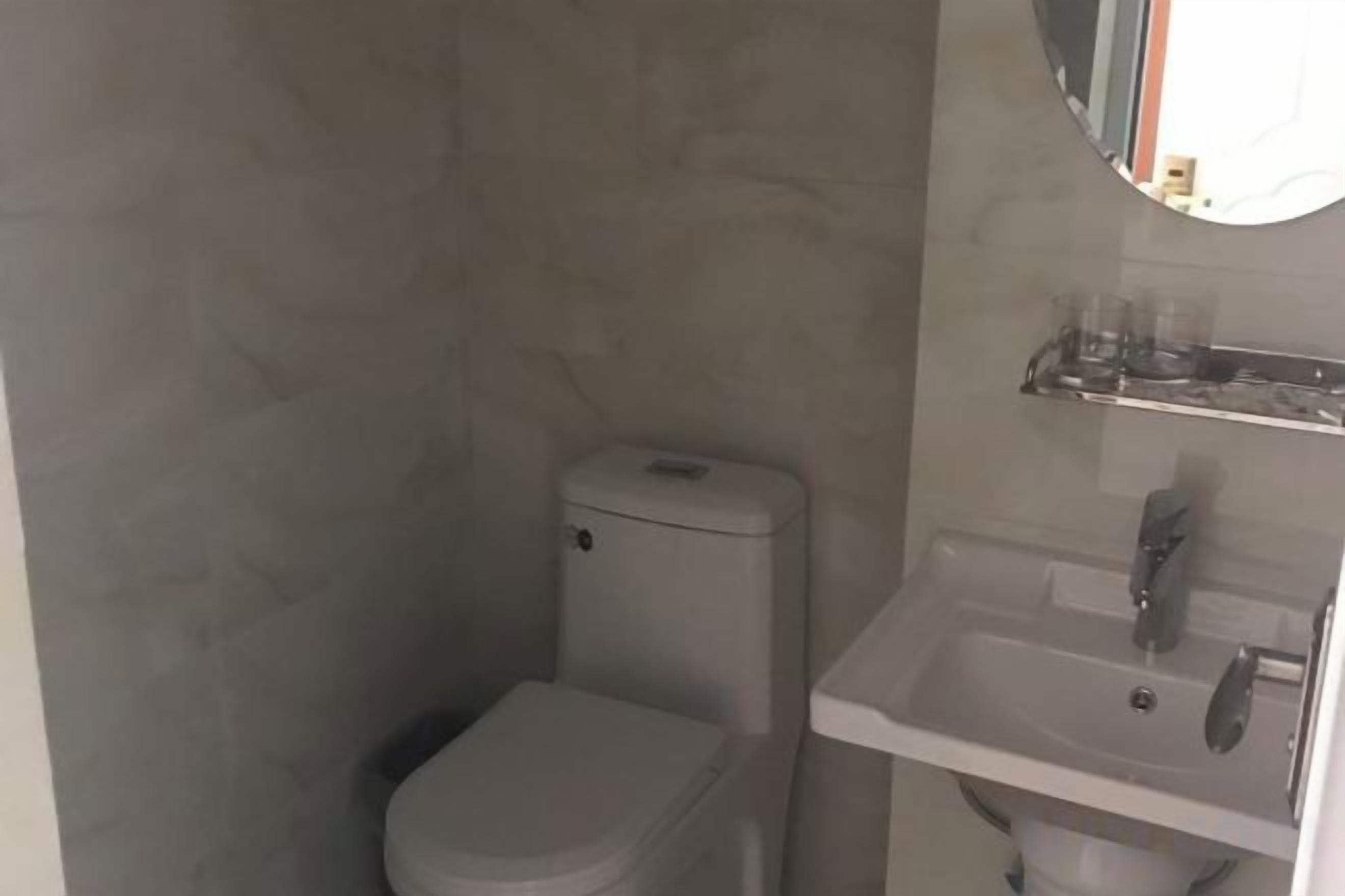A small bathroom with a toilet, sink, and a mirror.