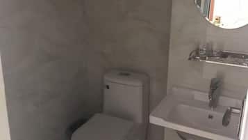 A small bathroom with a toilet, sink, and a mirror.