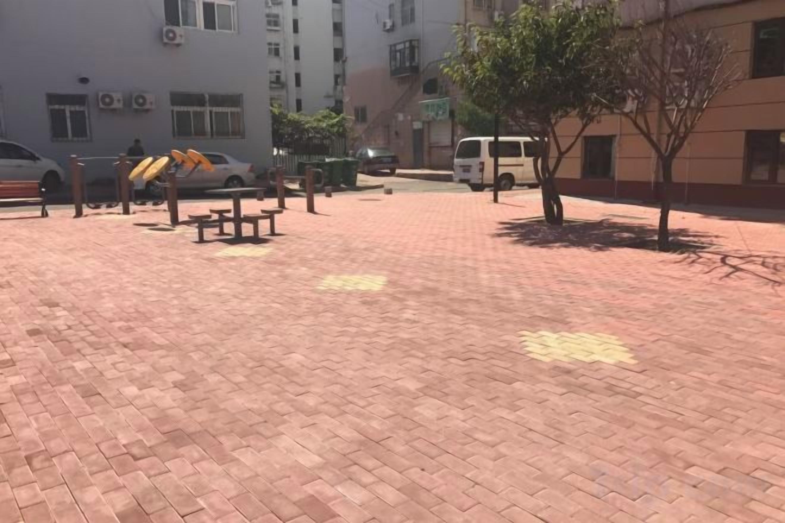A paved outdoor area with benches and a tree.