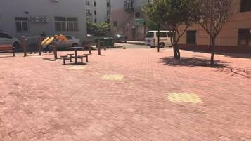 A paved outdoor area with benches and a tree.