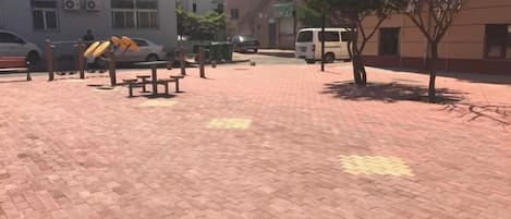 A paved outdoor area with benches and a tree.