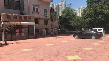 A building with a storefront, parked cars, and a paved area.
