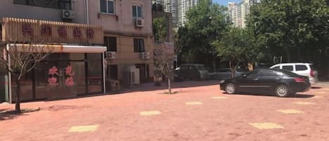 A building with a storefront, parked cars, and a paved area.