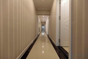 A long, narrow hallway with a reflective floor and striped walls. - Hongrunde Hotel (Qingdao)