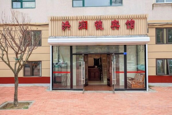 A hotel entrance with a glass door and a sign above. - Hongrunde Hotel (Qingdao)