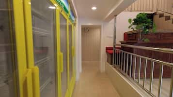 Un pasillo con una puerta amarilla, una escalera y una planta en la rellano.