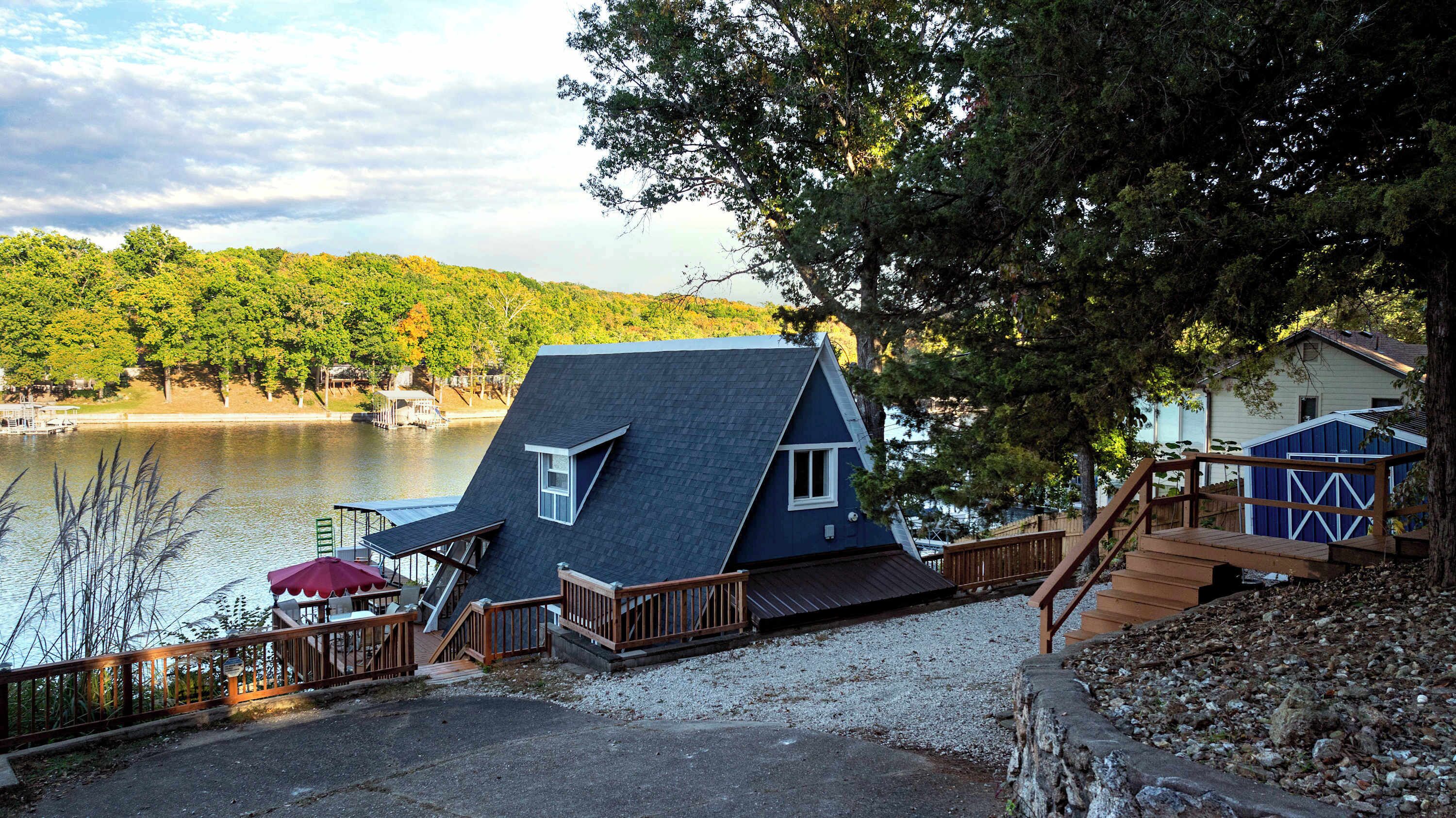A house with a steeply pitched roof, a deck, and a view of a lake.