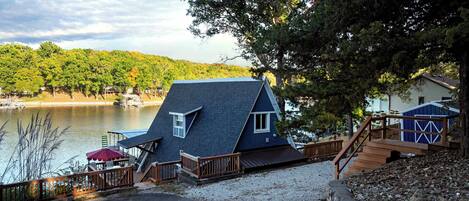 A house with a steeply pitched roof, a deck, and a view of a lake.