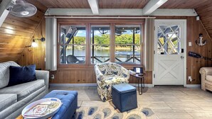 Ein gemütliches Zimmer mit Holzwänden, einem großen Fenster mit Seeblick, einem Ventilator und einer Tür mit einem Schild.