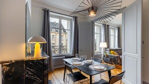 A dining area with a black marble table, four chairs, and a modern pendant light.