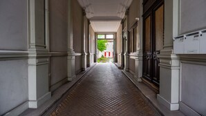 A corridor with a tiled floor, white walls, and a door with a dark frame.