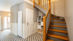 A staircase with wooden steps and a handrail, leading to a landing with a white door and a bookshelf. - L'Oasis De Calmont - Piscine Privée (Calmont)
