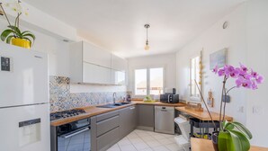 Una cocina moderna con armarios blancos, salpicadero de azulejos, horno empotrado y pileta.