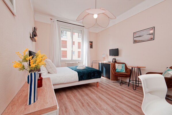Un dormitorio moderno con cama, mesita de noche, silla, escritorio y ventana con cortinas.