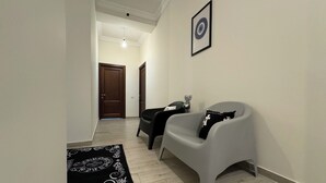 A hallway with a grey chair, a black and white patterned rug, and a framed picture on the wall. - Velvet Vouge Hostel (Yerevan)