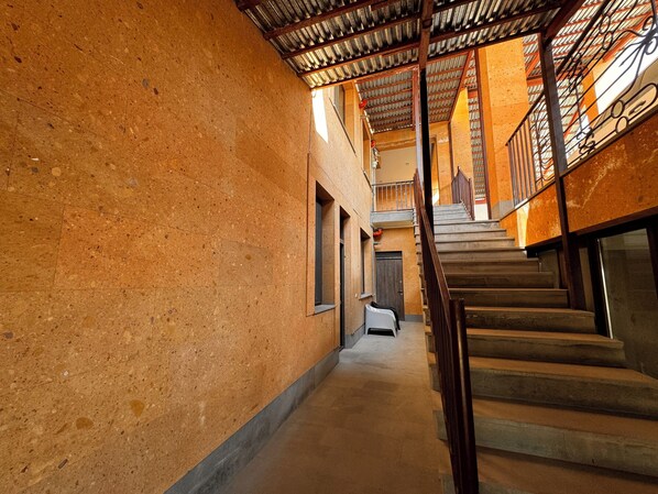 A narrow hallway with a staircase leading to an upper level. The walls are textured and the floor is tiled.
