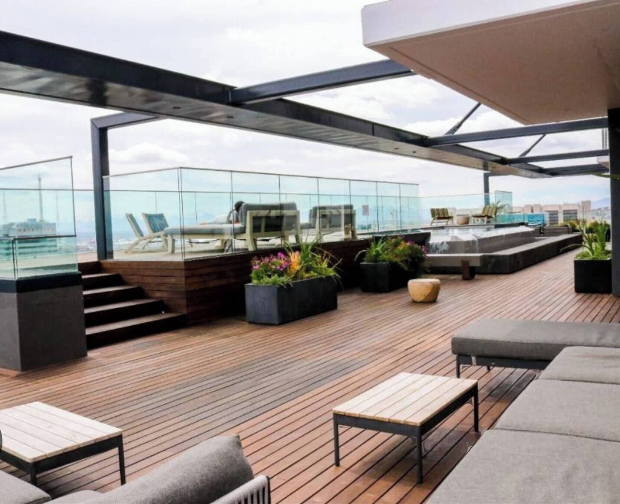 A rooftop terrace with wooden flooring, outdoor seating, and potted plants.
