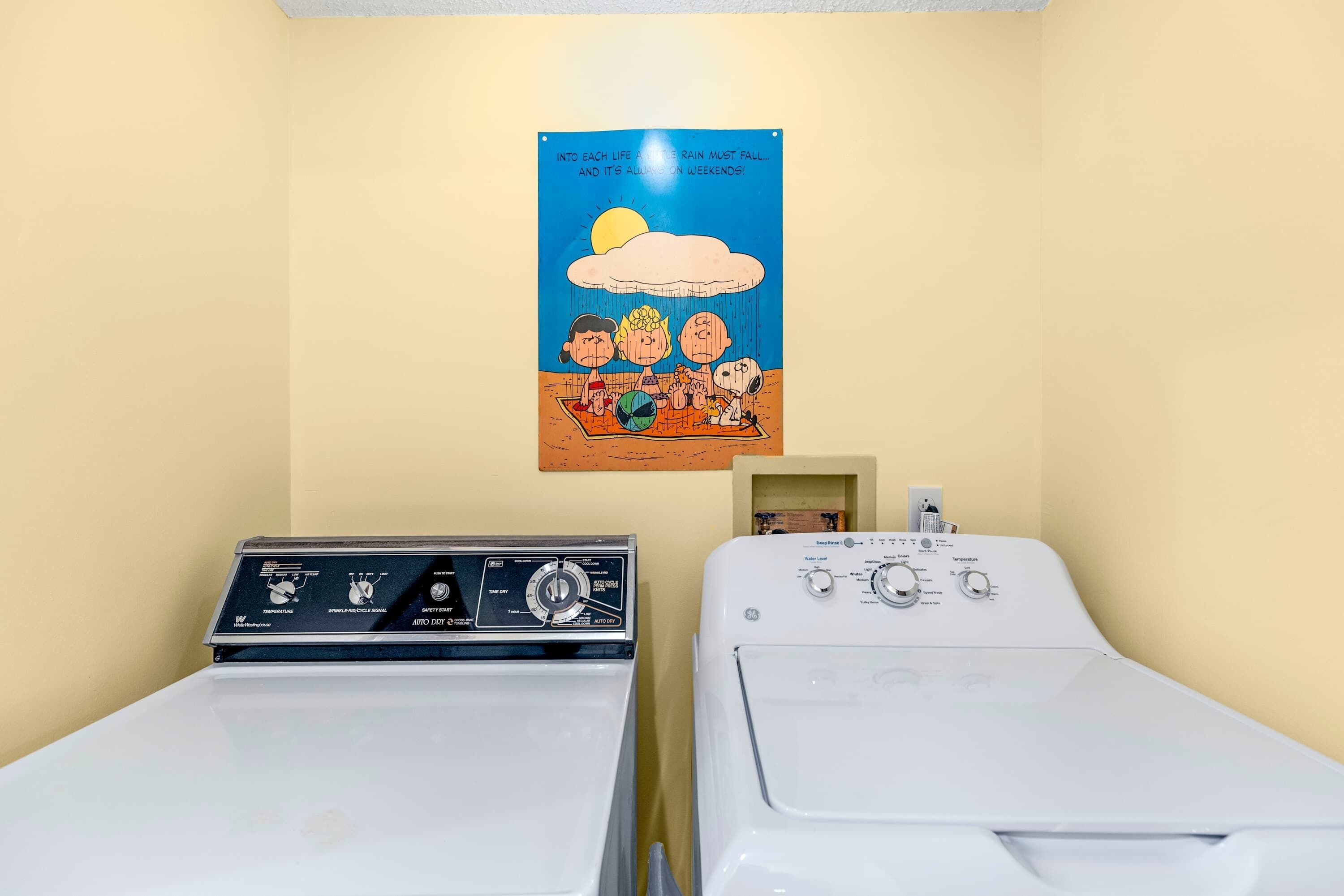 A laundry room with two washing machines and a poster on the wall.